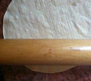 Flattening a tortilla with rolling pin.