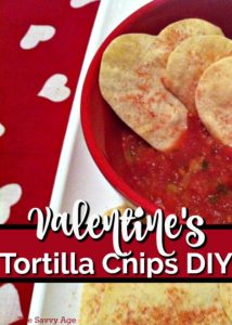 Heart shaped tortilla chips in a bowl of salsa.