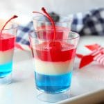 4th of July red, white and blue layered jello dessert in a clear glass.