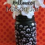 Halloween mason jar with googly eyes and white flowers.