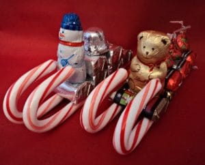 Two candy cane sleighs with chocolate presents and teddy bear driver.
