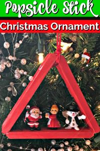 Popsicle stick christmas ornament decorated with mini santa.