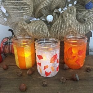 Mason jars decorated with leaves, orange and yellow stripes.