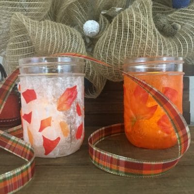 Two mason jars decorated with leaves.