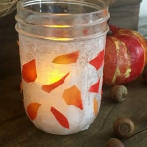 Glowing mason jar with decorated leaves.