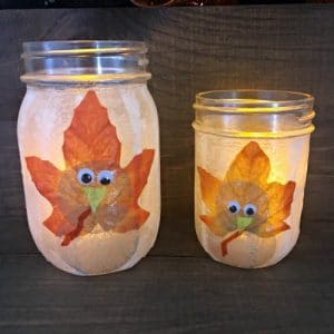 Two mason jars illuminated with handmade turkey on front.
