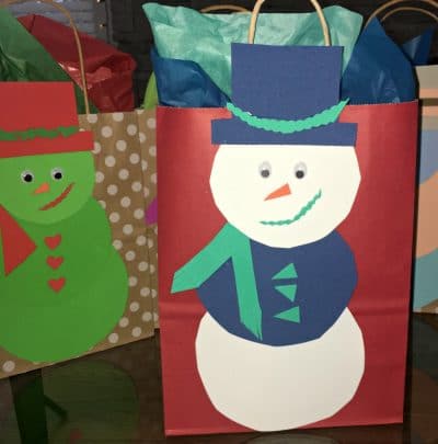 Handmade paper snowman on the outside of a gift bag.