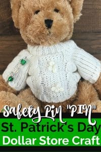 Teddy bear with cream irish cable sweater with a homemade pin made of a safety pin and green beads.