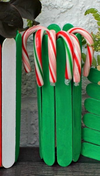 Green vase made of popsicle sticks and filled with candy canes.