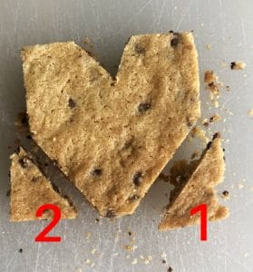 Heart shaped chocolate chip cookie on white background. Number 1 and 2 at each corner to mark cut lines.