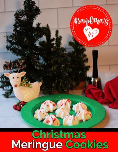 Star shaped white meringue cookies on a green plate in front of mini green trees and a reindeer ornament.